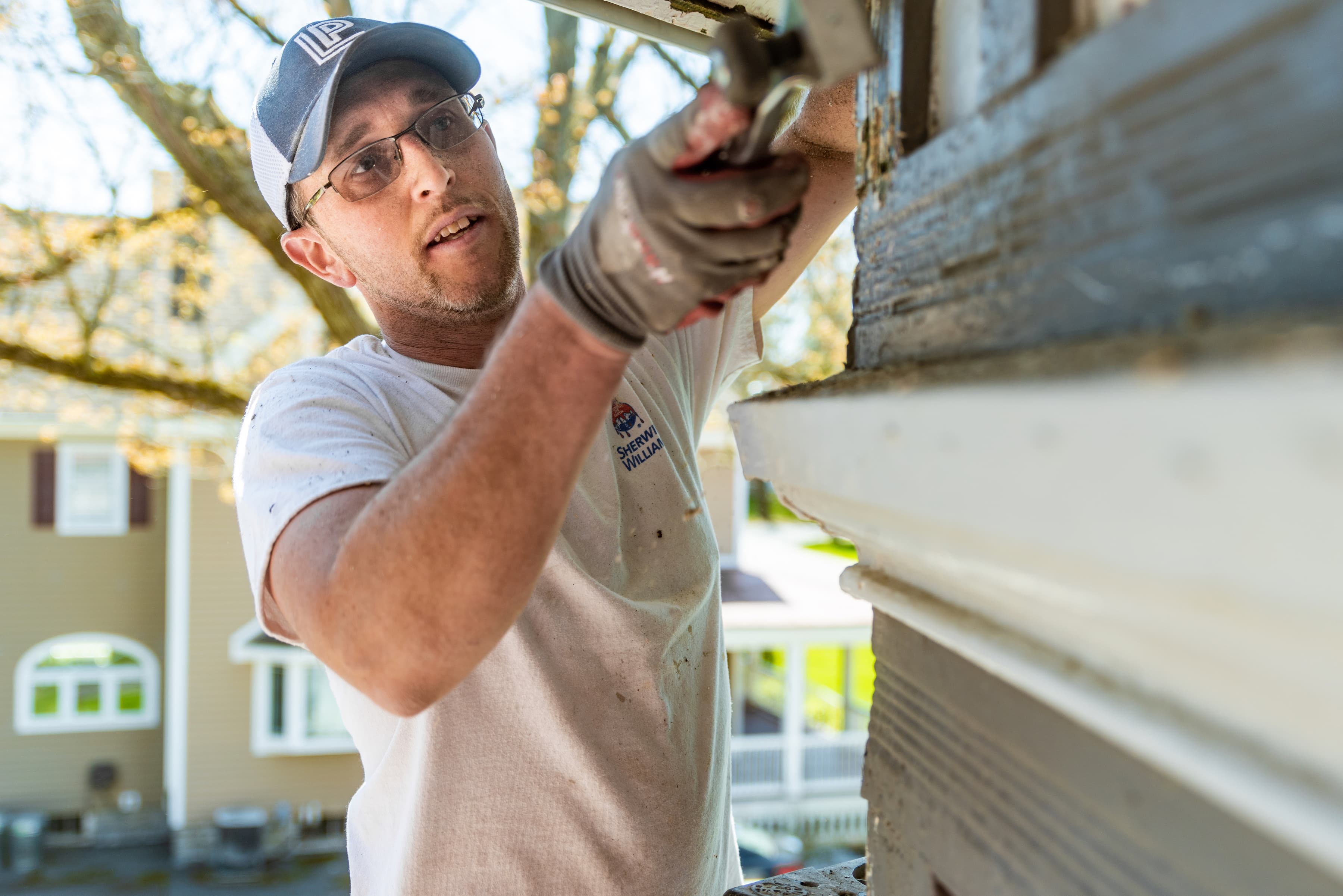 A person scraping paint off building