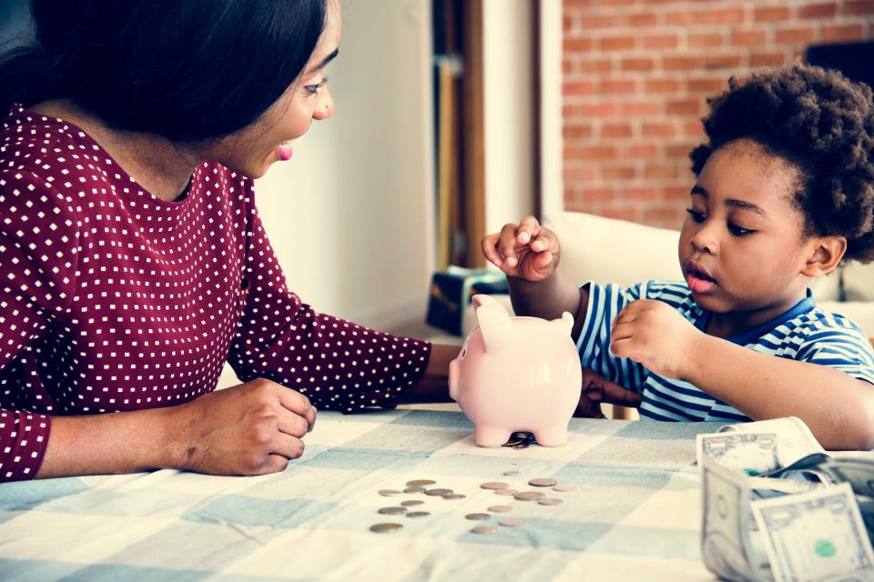 Mother and child putting money in a piggy bank