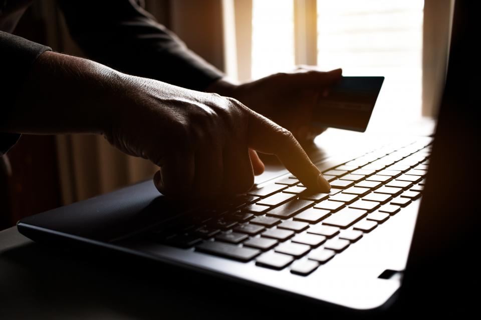 Typing on keyboard with credit card in hand