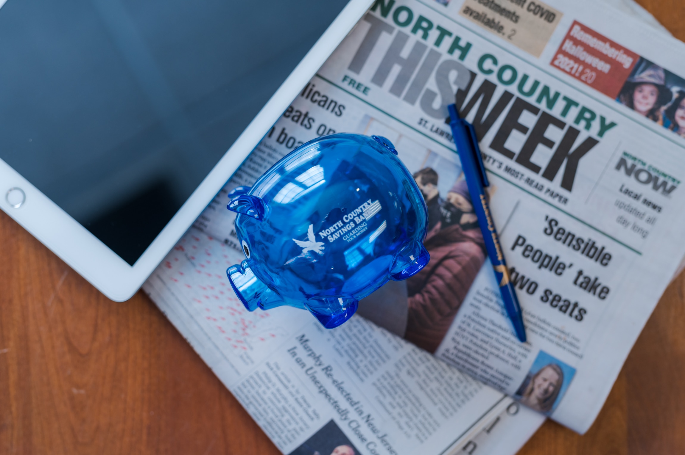 Tablet and newspaper and piggy bank on table